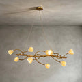 Lit Clérachic magnolia chandelier hung from a gold canopy on fine wires, against a soft grey plaster wall.