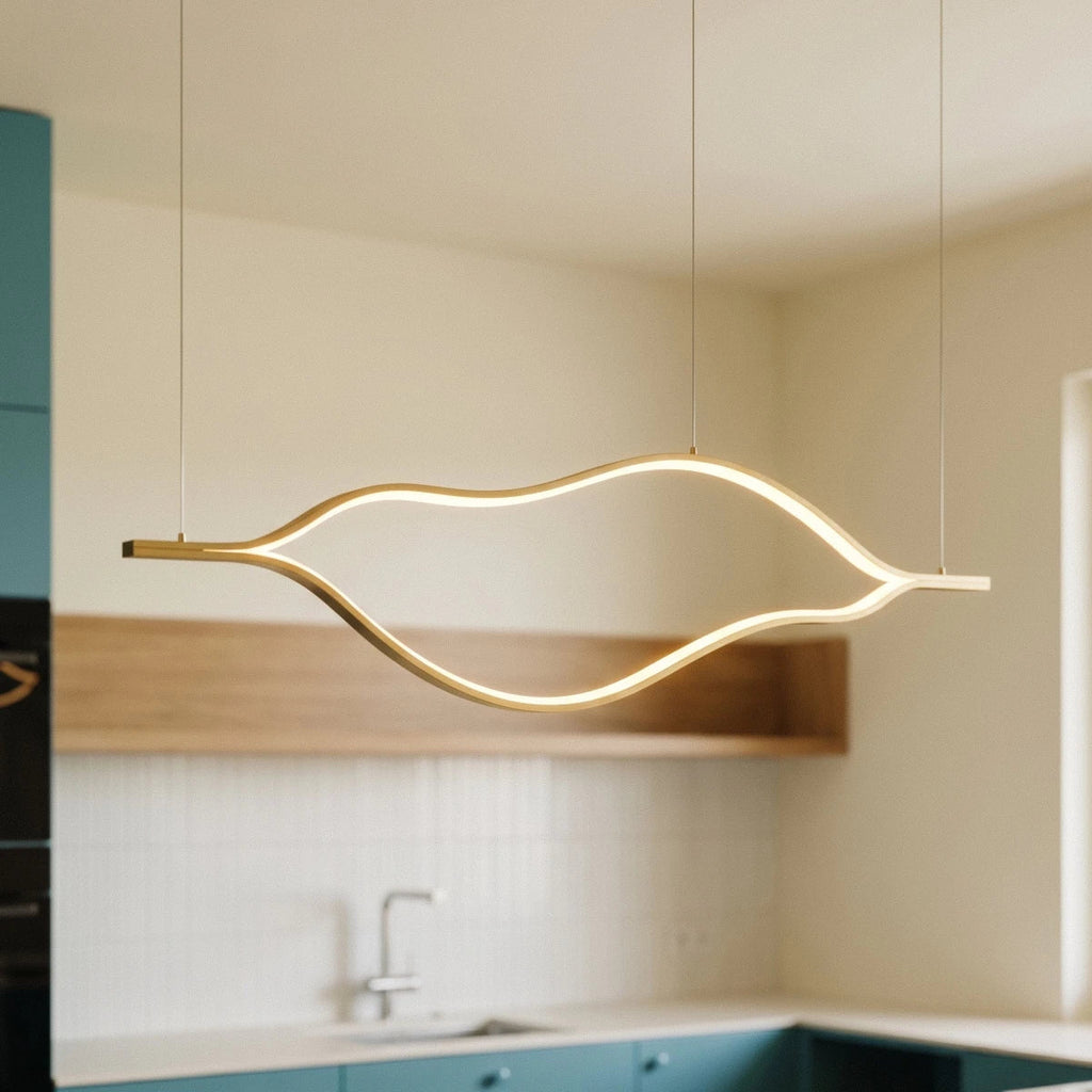 Close view of the Clérachic gold linear chandelier, its slim brushed metal frame and glowing LED strip tracing a wave over a kitchen.