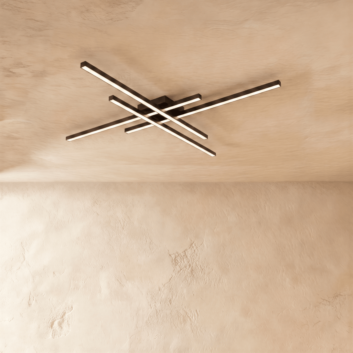 Clérachic black ceiling light of four crossed LED bars glowing warm white on a limewash ceiling, seen from below.