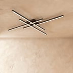 Clérachic black crossed-bar LED ceiling light in a long size, four glowing bars fixed flush to a limewash ceiling.