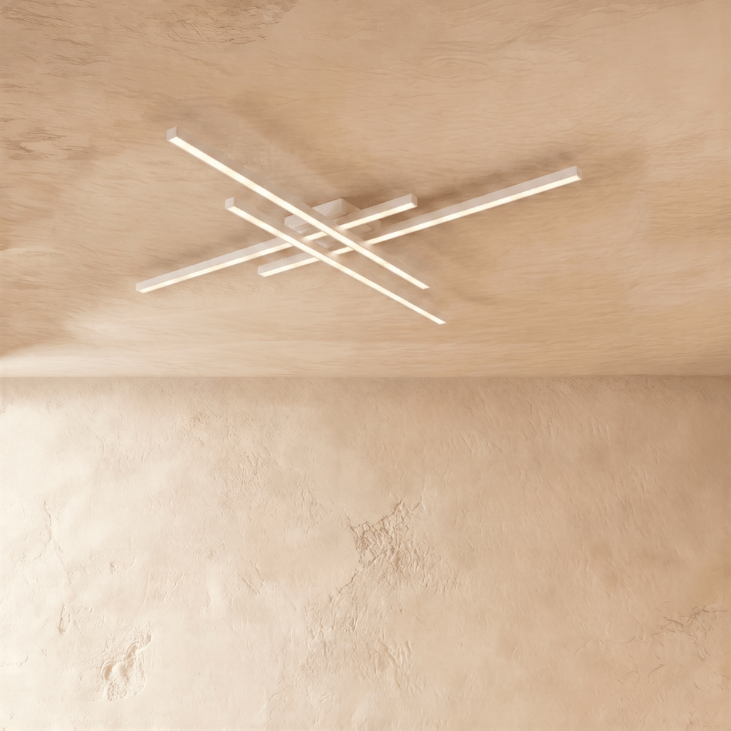 Clérachic white ceiling light of four crossed LED bars, slim aluminium arms glowing soft white on a limewash ceiling.