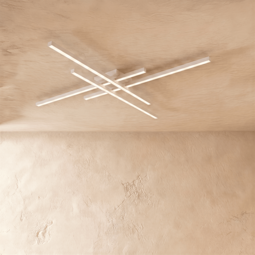 Clérachic white four-bar LED ceiling light in a larger size, thin crossed aluminium arms lit softly on limewash.