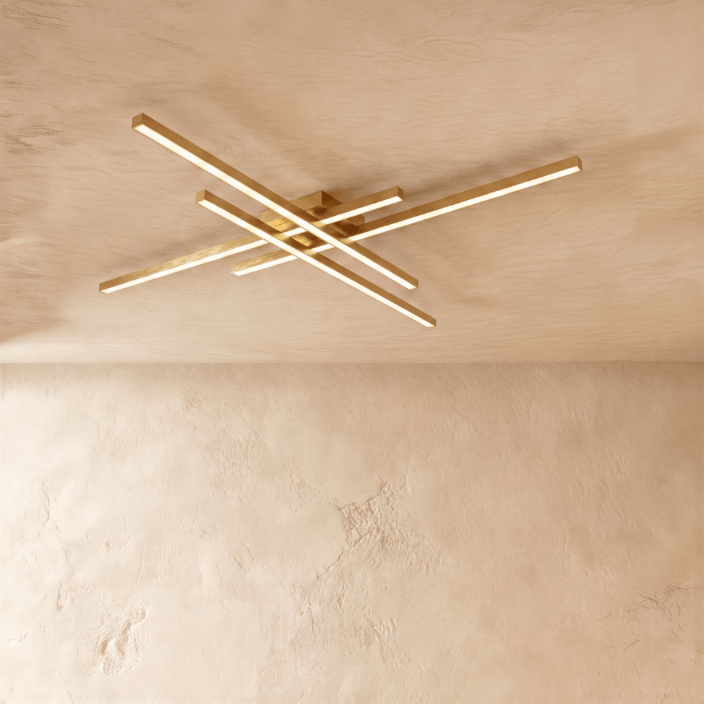 Clérachic gold crossed-bar LED ceiling light in a larger size, four brass-toned bars lit warm on limewash.