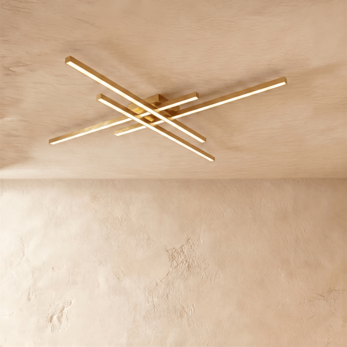 Clérachic gold crossed-bar LED ceiling light in a larger size, four brass-toned bars lit warm on limewash.