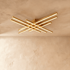 Clérachic wide gold six-bar LED ceiling light, layered brass-toned bars with frosted diffusers lit on limewash.