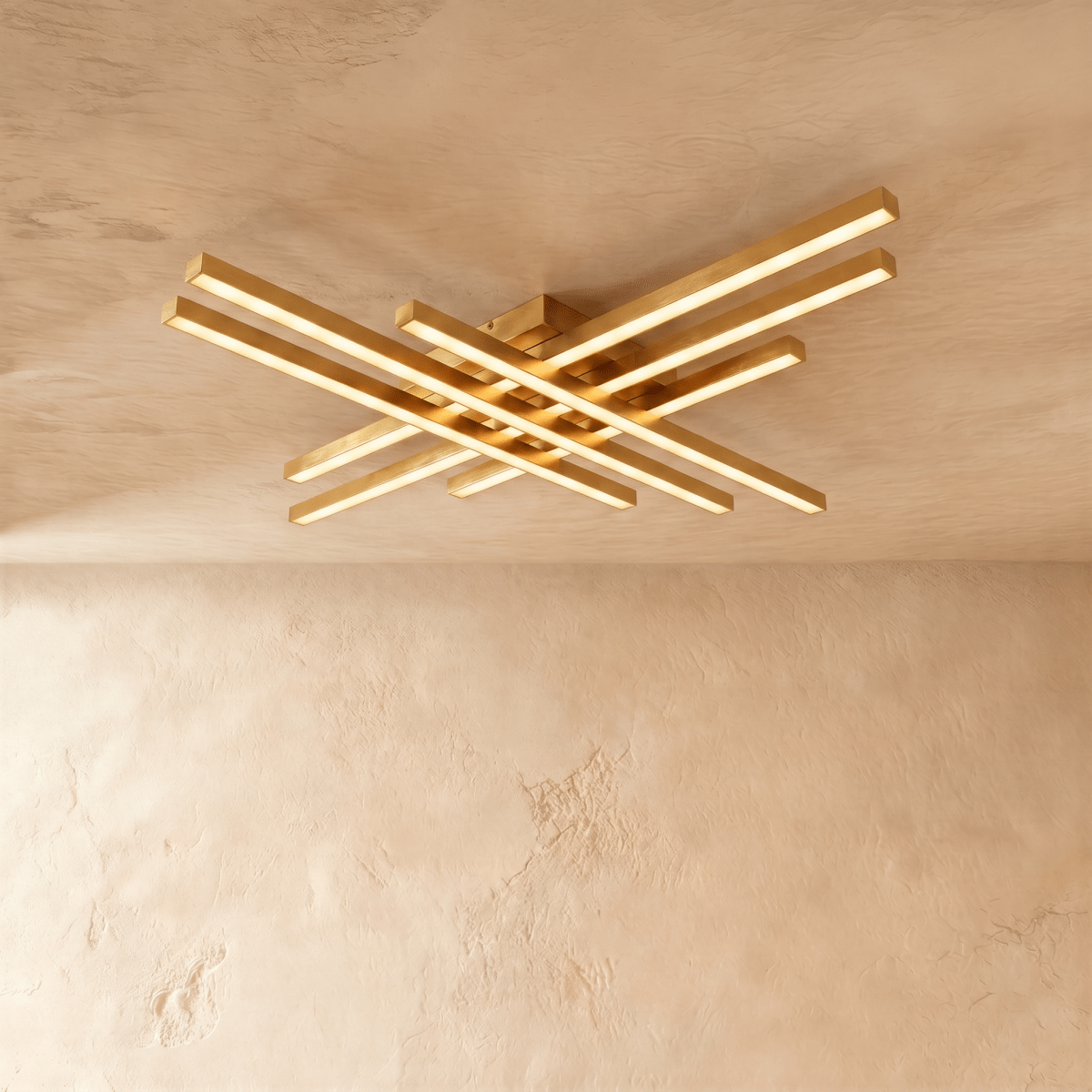 Clérachic wide gold six-bar LED ceiling light, layered brass-toned bars with frosted diffusers lit on limewash.