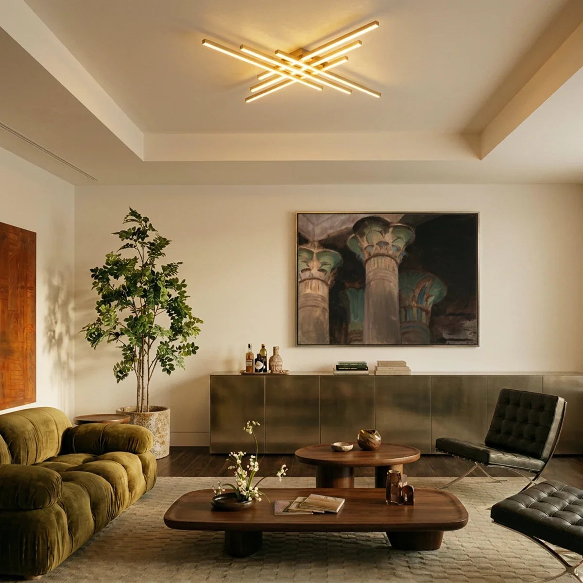 Clérachic gold six-bar LED ceiling light over a living room with an olive velvet sofa, walnut tables and a framed painting.