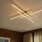 Clérachic gold four-bar LED ceiling light close up, glowing frosted bars on a ceiling beside walnut panelling and curtains.