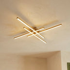 Clérachic gold four-bar LED ceiling light from below, brushed brass bars with soft frosted light on a limewash ceiling.