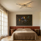 Clérachic black six-bar LED ceiling light above a bed with a linen cover, terracotta headboard and a large framed artwork.
