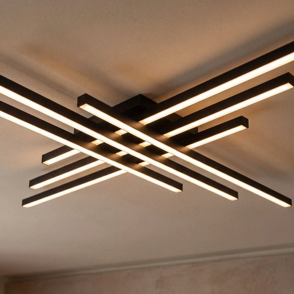 Clérachic black six-bar LED ceiling light close up, layered crossed bars with frosted diffusers lit warm on a ceiling.
