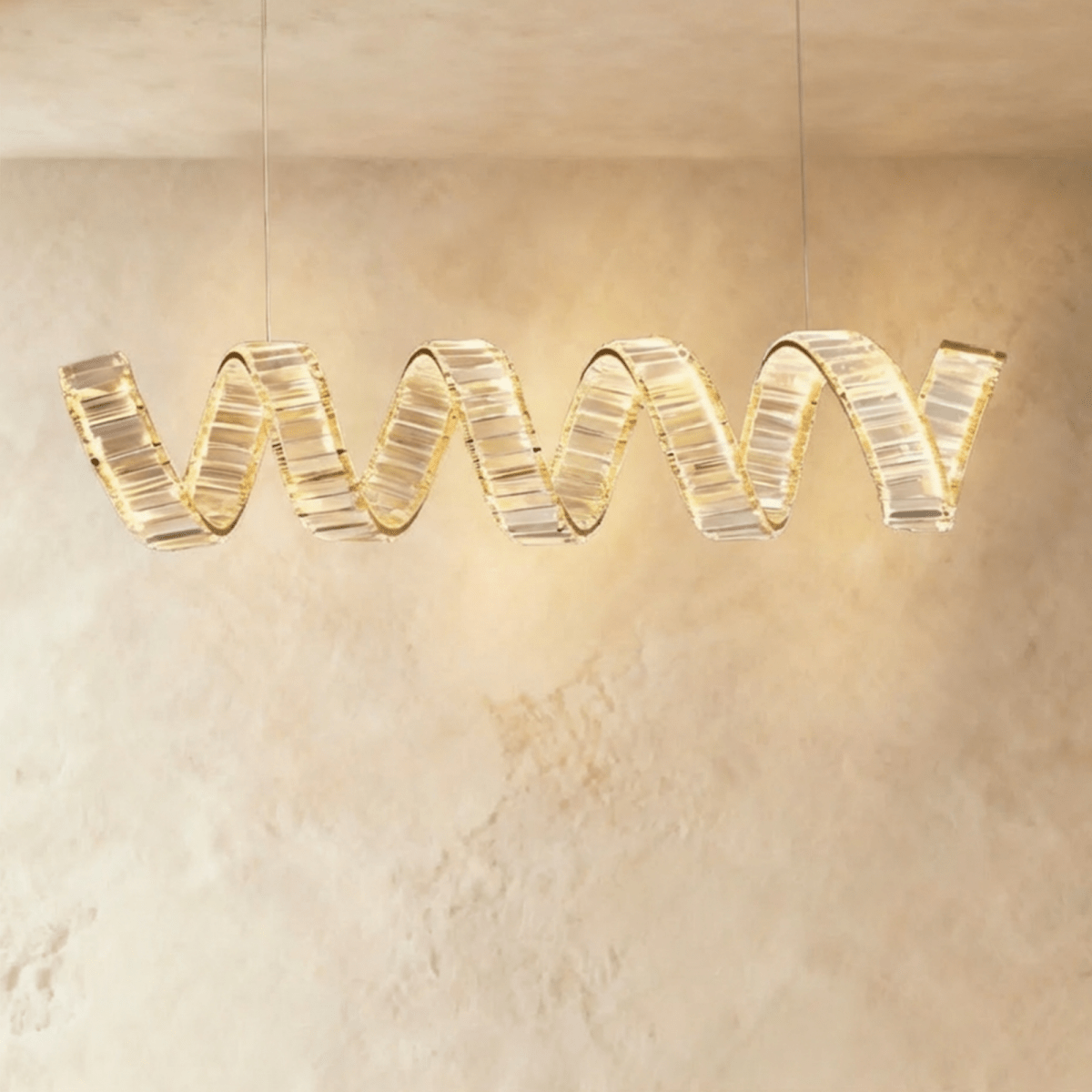 Clérachic longest single-wave spiral chandelier in gold, its crystal ribbon glowing warm under a pale plaster ceiling.