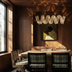 Clérachic single-wave crystal chandelier over a timber dining table, dappled sunlight falling across the panelling.