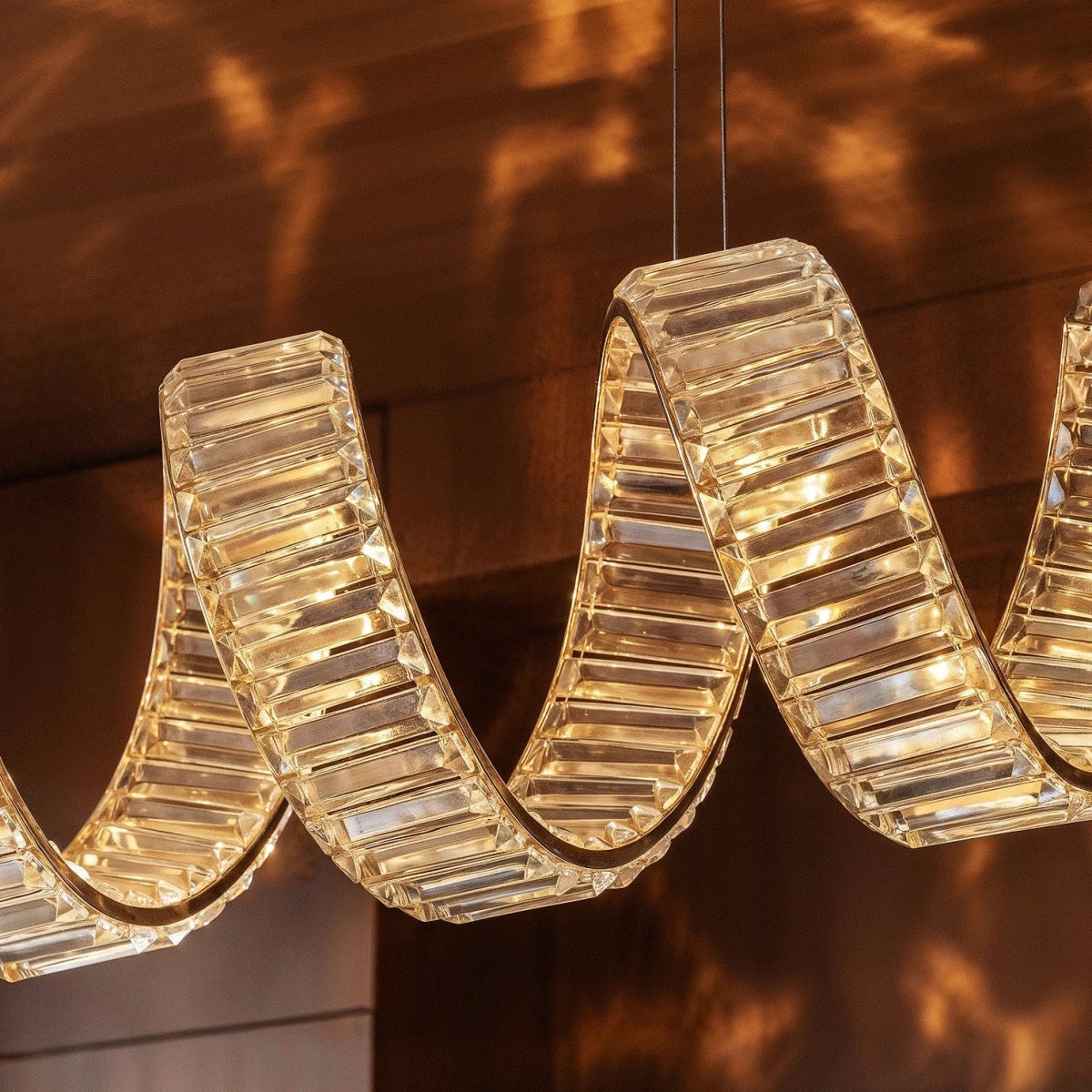 Clérachic close-up of faceted crystal blocks along a looping ribbon, warm light glowing through each facet.