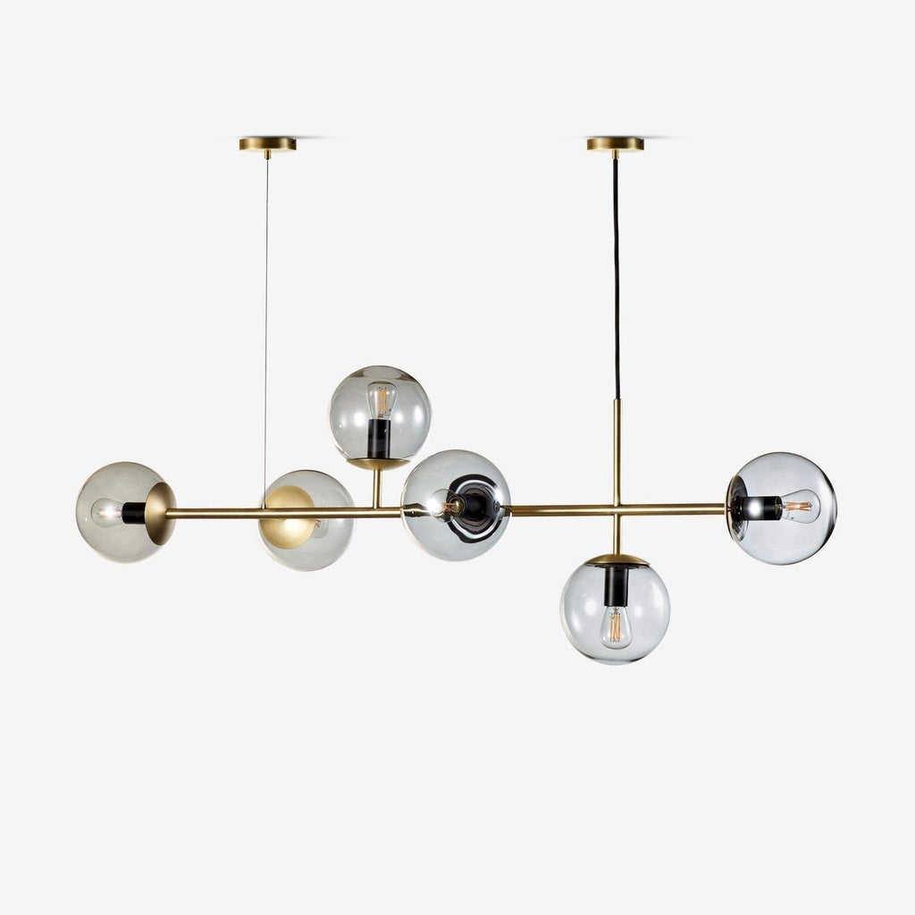 Six smoky glass orbs on a slim brass rod, hung from two ceiling canopies on a plain white backdrop, from Clérachic.