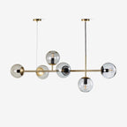 Six smoky glass orbs on a slim brass rod, hung from two ceiling canopies on a plain white backdrop, from Clérachic.