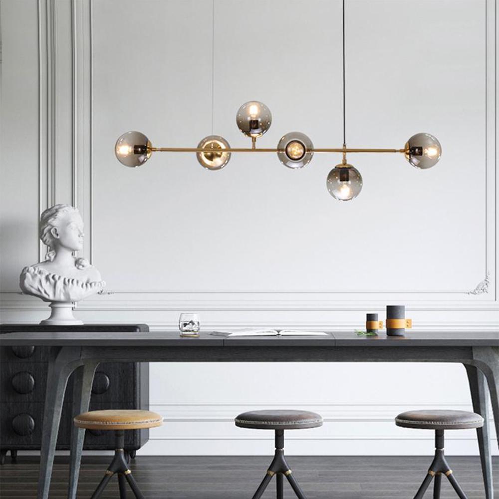 This Clérachic pendant shows six smoked orbs on a brass rod above a dark console table with three round-seat stools.