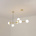 A Clérachic pendant with six frosted white orbs on a brass rod, photographed from below against a cream ceiling corner.