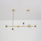 Clear glass orbs along a brass rod, hung from two round ceiling canopies against a white wall, in this Clérachic pendant.