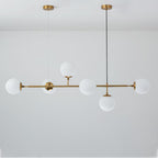 Six opal white glass orbs on a brass rod, hung from two canopies against a pale grey wall in this Clérachic pendant.