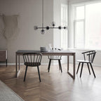 A black-bar version of this Clérachic pendant with smoked orbs hangs in a bright room over a grey table and black spindle chairs.