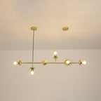 Switched on, the clear orbs of this Clérachic pendant cast a warm amber glow along the brass rod in a cream-toned room.