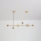 Unlit clear glass orbs show their bulb holders along the brass rod of this Clérachic pendant, with a white room behind.