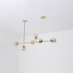 Six amber-tinted glass orbs cluster along the brass rod of this Clérachic pendant, photographed in a white room corner.