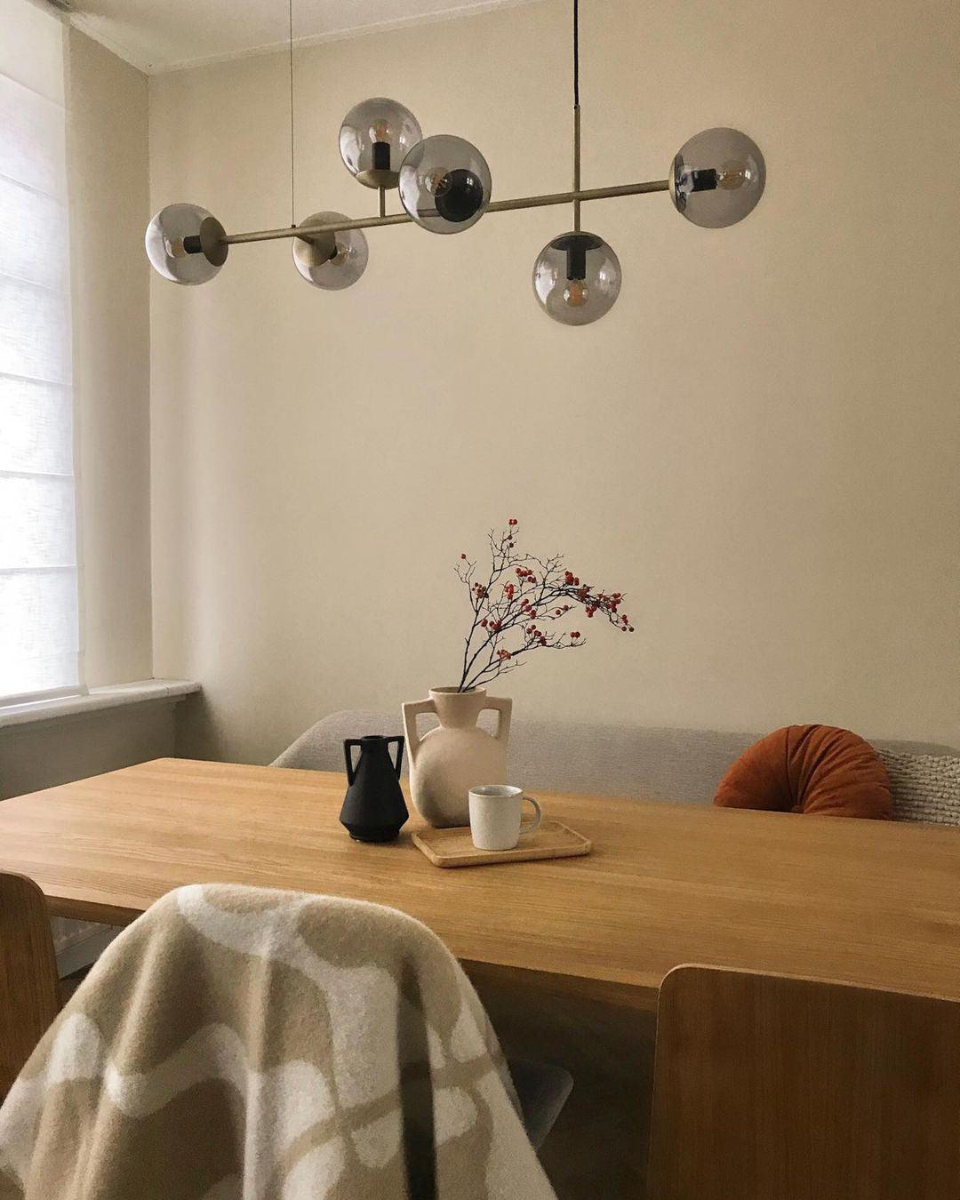 Smoke-grey orbs on a slender brass rod, hung over a light oak table with a vase of berries, in this Clérachic pendant.