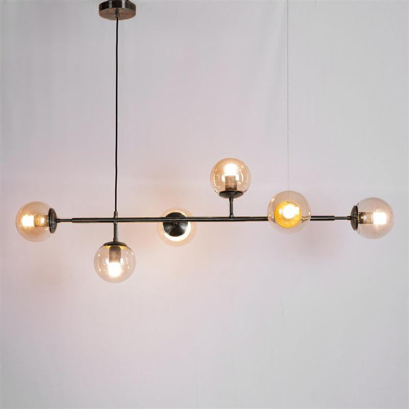 Black bar and amber orbs glowing warm, hung on a black cord in this Clérachic pendant against a plain grey backdrop.