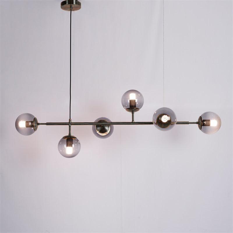 A black-bar Clérachic pendant with smoke-grey orbs, each with a lit bulb, hanging on a black cord against a plain backdrop.