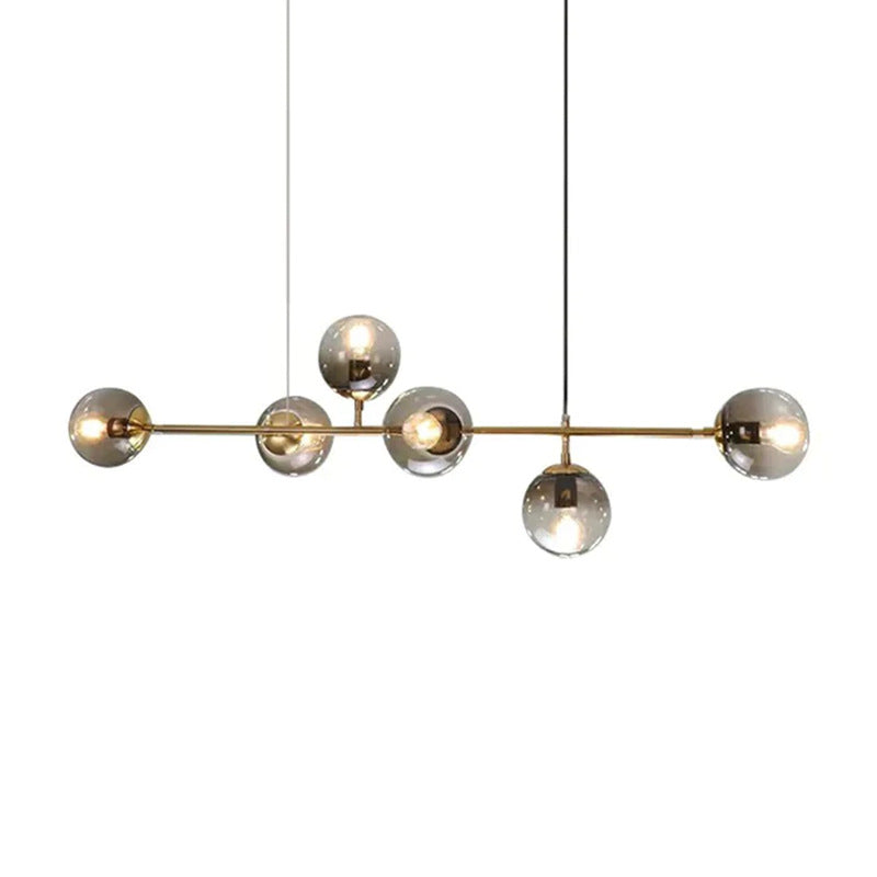 Smoked glass orbs of graduated grey sit on the brass bar of this Clérachic pendant, shown cut out on a white backdrop.