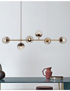 Close to a pale wall, this Clérachic pendant's six smoke-grey orbs hang above a dark blue console and a terracotta jug.