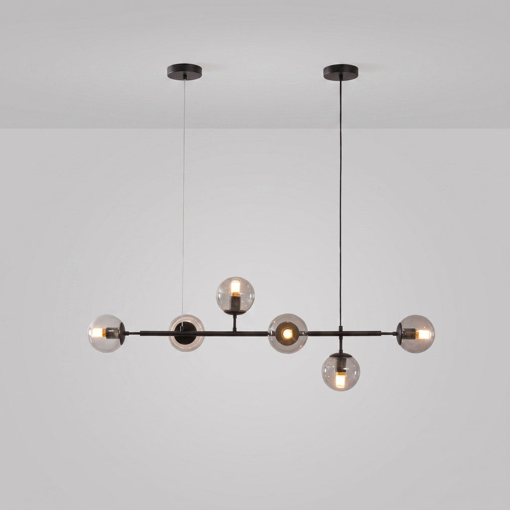 A Clérachic pendant in black, with a black rod and canopies, six clear-tinted orbs lit on a light grey studio backdrop.