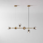 Straight-on studio view of this Clérachic pendant, with its brass rod, two canopies and six lit clear orbs on pale grey.