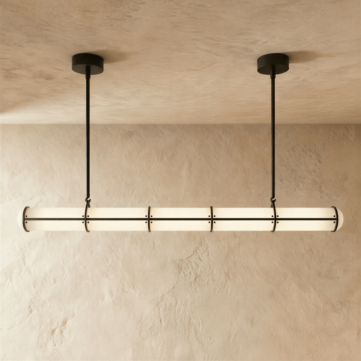 Clérachic extra-long opal tube pendant with black bands and two slim hanging rods, glowing softly in front of a textured wall.