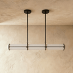 Clérachic black-banded opal tube pendant on two slim rods, shown at its shorter length against a warm plaster backdrop.
