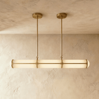 Clérachic opal tube pendant in a gold finish, its slim rods and ceiling plates echoing the banded frame over a plaster wall.