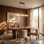 Clérachic black-framed opal tube pendant over a walnut dining table, with bouclé chairs, panelled walls and a large painting.