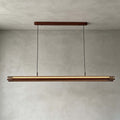 Straight-on view of this Clérachic linear pendant, a lit walnut and gold bar hung from a long walnut canopy, on a grey wall.