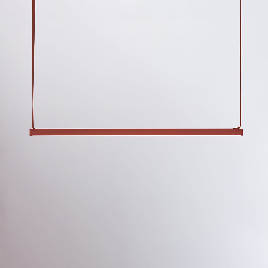 A red bar of this Clérachic linear pendant light hangs from two red straps against a pale lilac-grey wall.