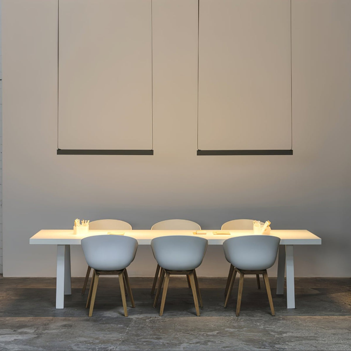 A wider view of two black bars of this Clérachic linear pendant light above a white table and pale blue chairs.