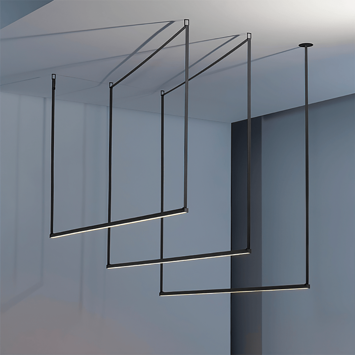 Three black bars from this Clérachic linear pendant light hang in a staggered frame in a blue-grey room, lit along their undersides.
