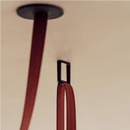 Close view of the red woven strap of this Clérachic linear pendant light passing through a dark ceiling fitting.