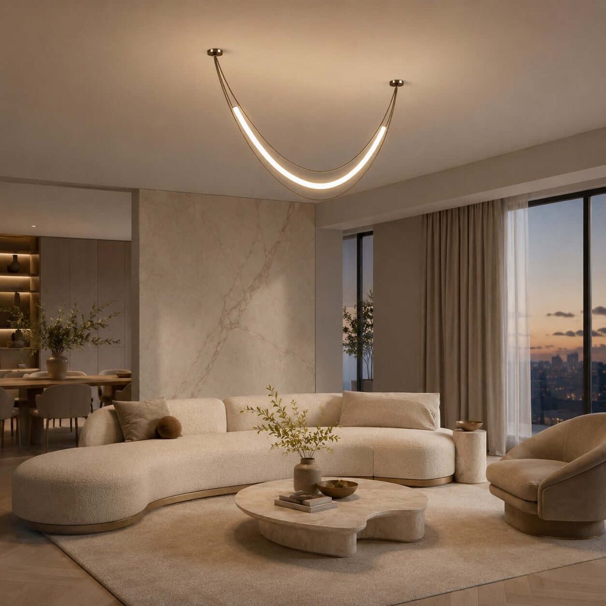 A single gold Clérachic curved light tube hung from two canopies over a curved cream sofa, with a city dusk view in the window.