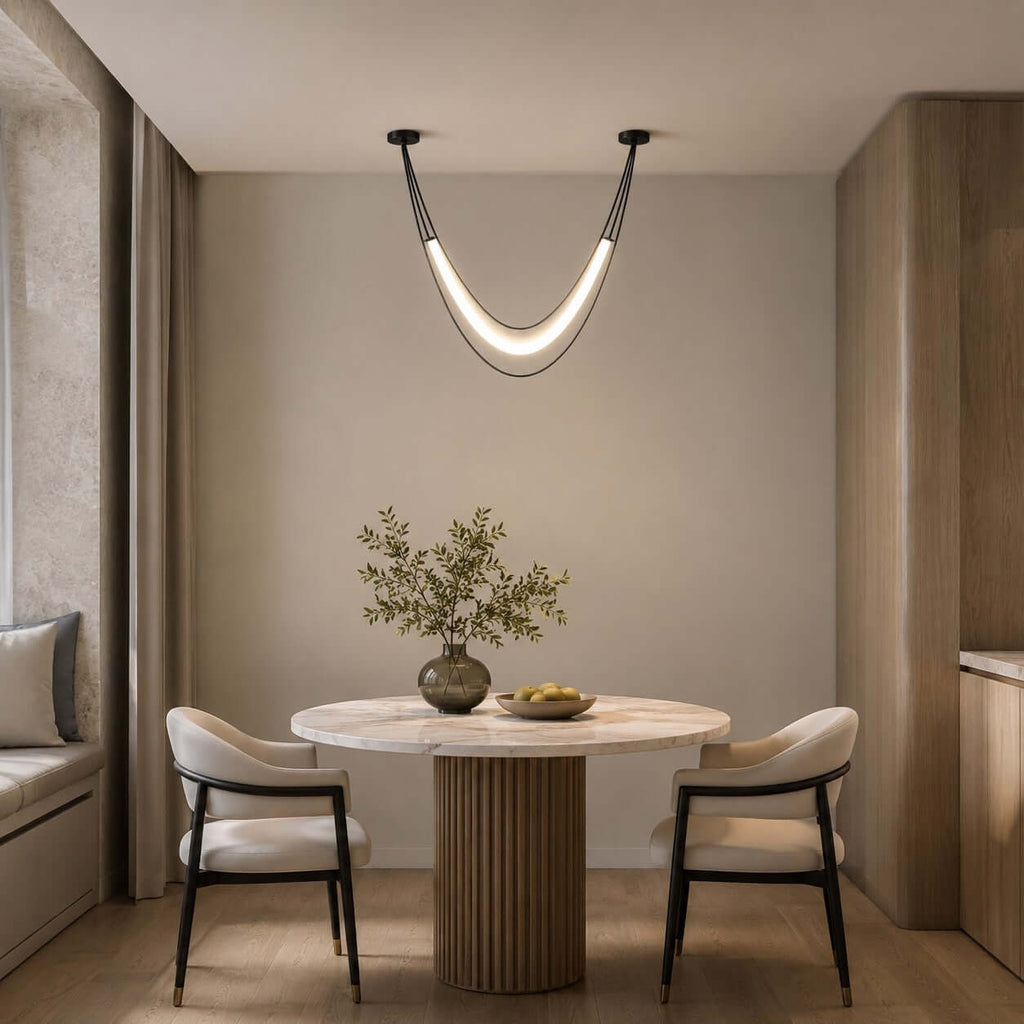 Black and white Clérachic hammock-shaped pendant above a small round pedestal table with two black-framed chairs.