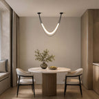 Black and white Clérachic hammock-shaped pendant above a small round pedestal table with two black-framed chairs.