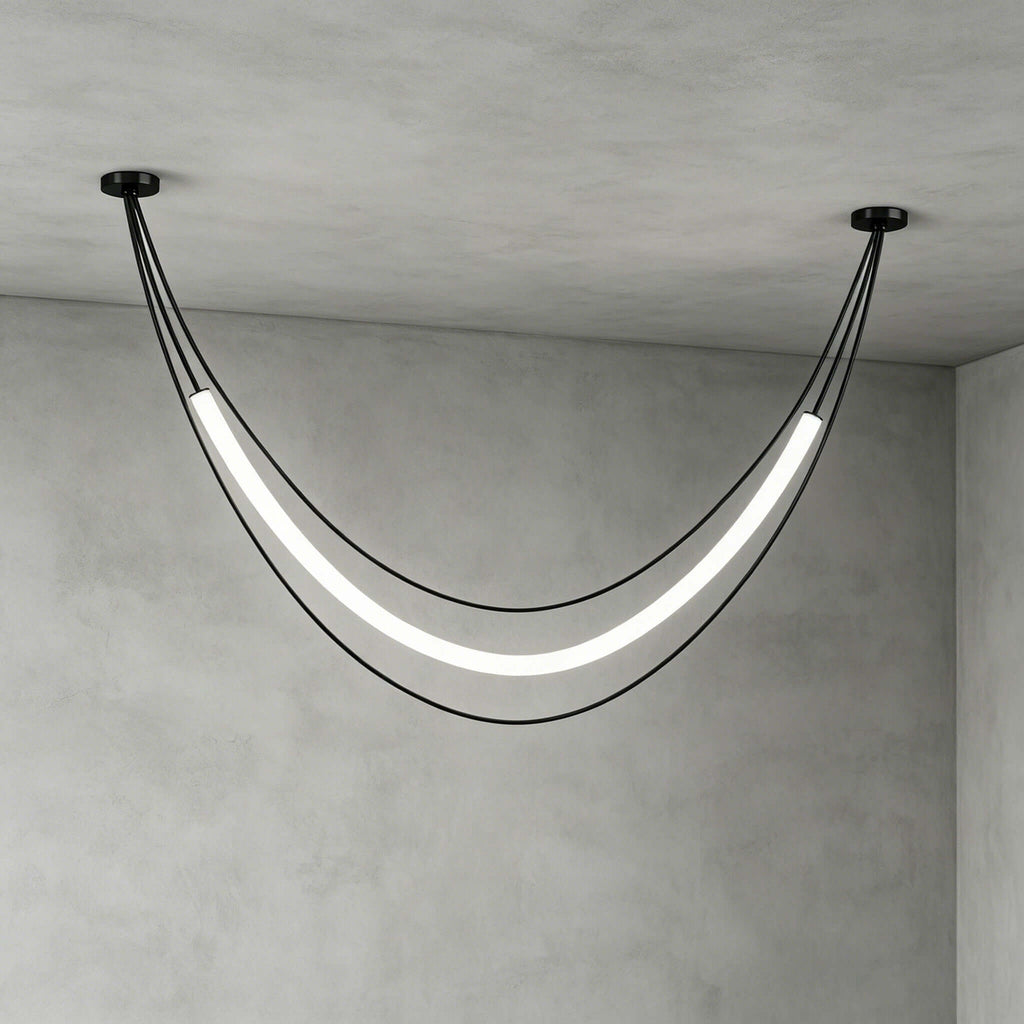 Black Clérachic pendant in its widest curve, a glowing tube between two ceiling canopies, against grey plaster walls.