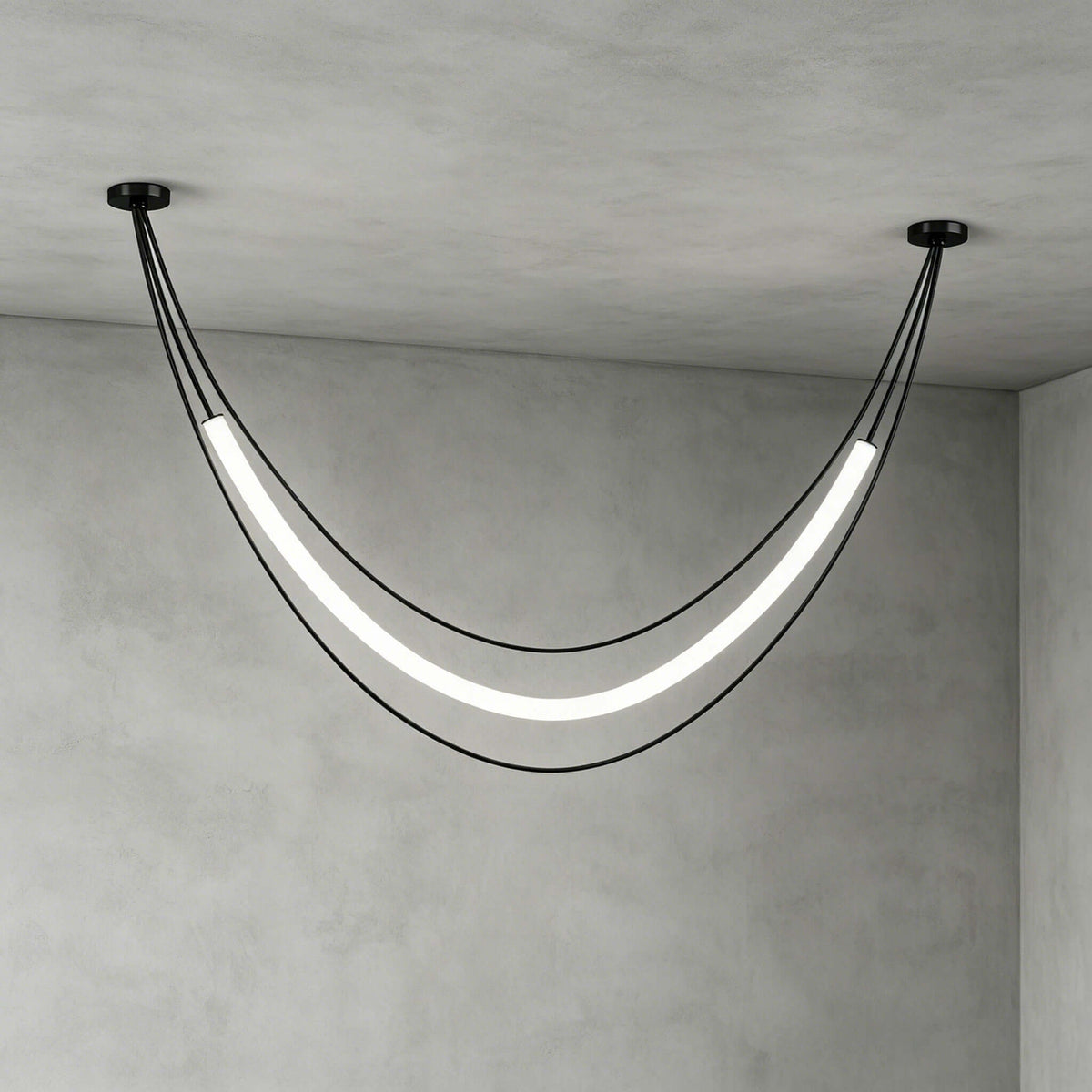 Black Clérachic pendant in its widest curve, a glowing tube between two ceiling canopies, against grey plaster walls.