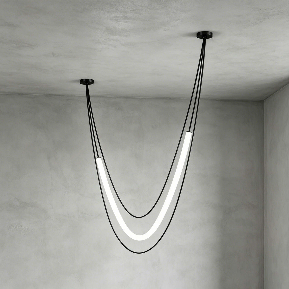 Deep, narrow black Clérachic pendant with its lit tube hanging low from uneven ceiling points, against grey plaster walls.